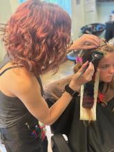 hairstyling student at work on her client's rainbow holographic prism hair stripes brantford hair school hairstylist hair dresser beauty college hairstyling diploma